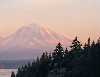 A mountain beyond a forested shoreline at dusk